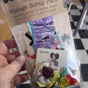 A package of vintage paper, cards, buttons, and other trinkets with a brown label that says "Vintage Scrap Pack."